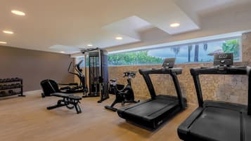Une salle de sport équipée de tapis de course, d’un banc de musculation et d’un support pour les exercices de squat.