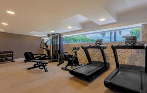 Une salle de sport équipée de tapis de course, d’un banc de musculation et d’un support pour les exercices de squat.