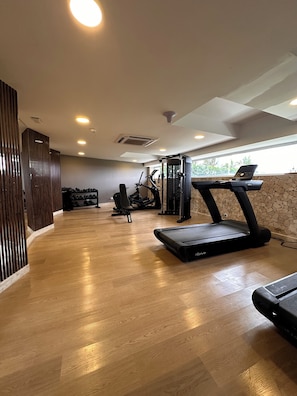 A gym with exercise equipment, wooden flooring, and a stone wall. - AC Hotel by Marriott Cartagena Colombia (Cartagena)