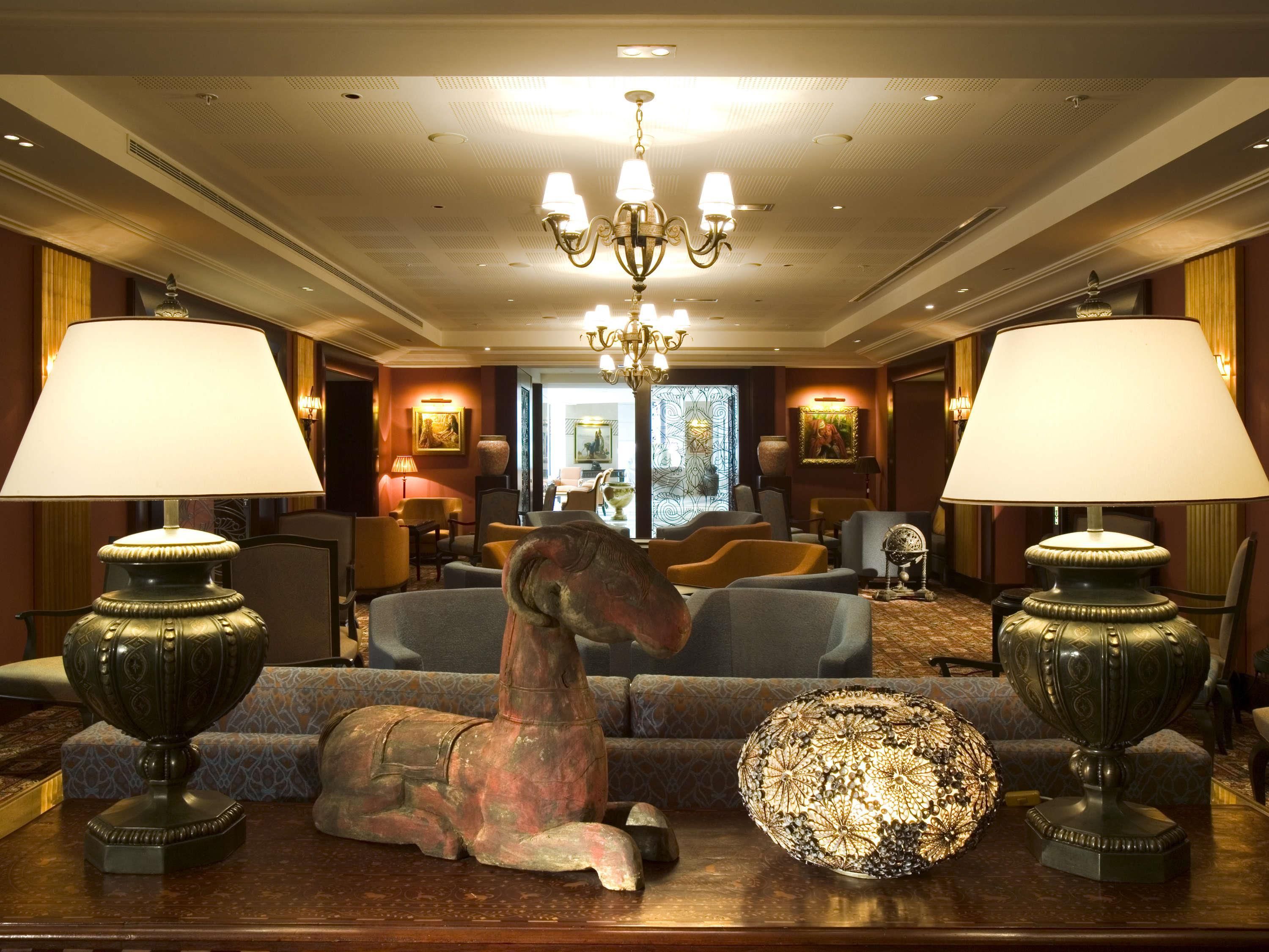 Un vestíbulo de hotel con una araña, dos lámparas, un sofá y un globo decorativo.