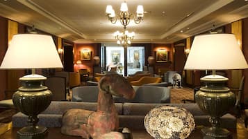 Un vestíbulo de hotel con una araña, dos lámparas, un sofá y un globo decorativo.
