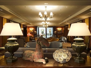 A hotel lobby with a chandelier, two lamps, a sofa, and a decorative horse statue. - Royal Hotel Oran - MGallery Collection (Oran)
