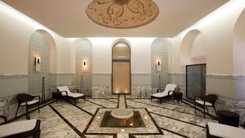 A spa room with a central hot tub, seating areas, and a decorative ceiling.