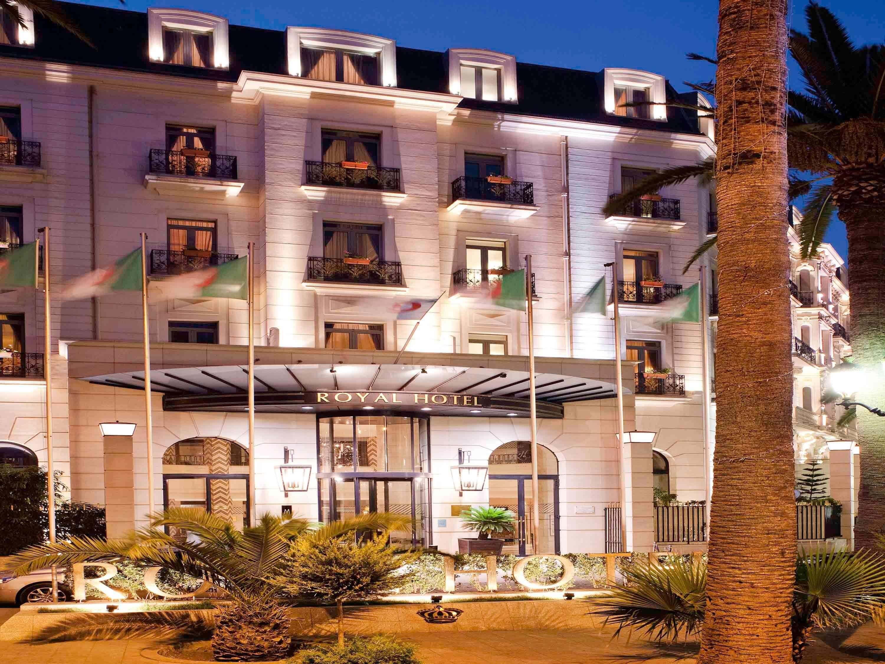 Un hotel amb una façana clàssica, diversos balcons i un vestíbul ben il·luminat.