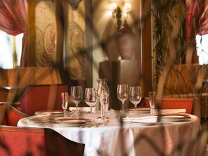 A dining table set with glasses, plates, and cutlery, with a patterned tablecloth. - Royal Hotel Oran - MGallery Collection (Oran)