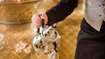Una persona sirve té en vasos sobre una bandeja decorativa.