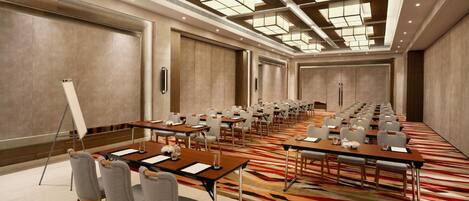 A conference room with multiple tables and chairs, a large carpeted floor, and a high ceiling with recessed lighting.