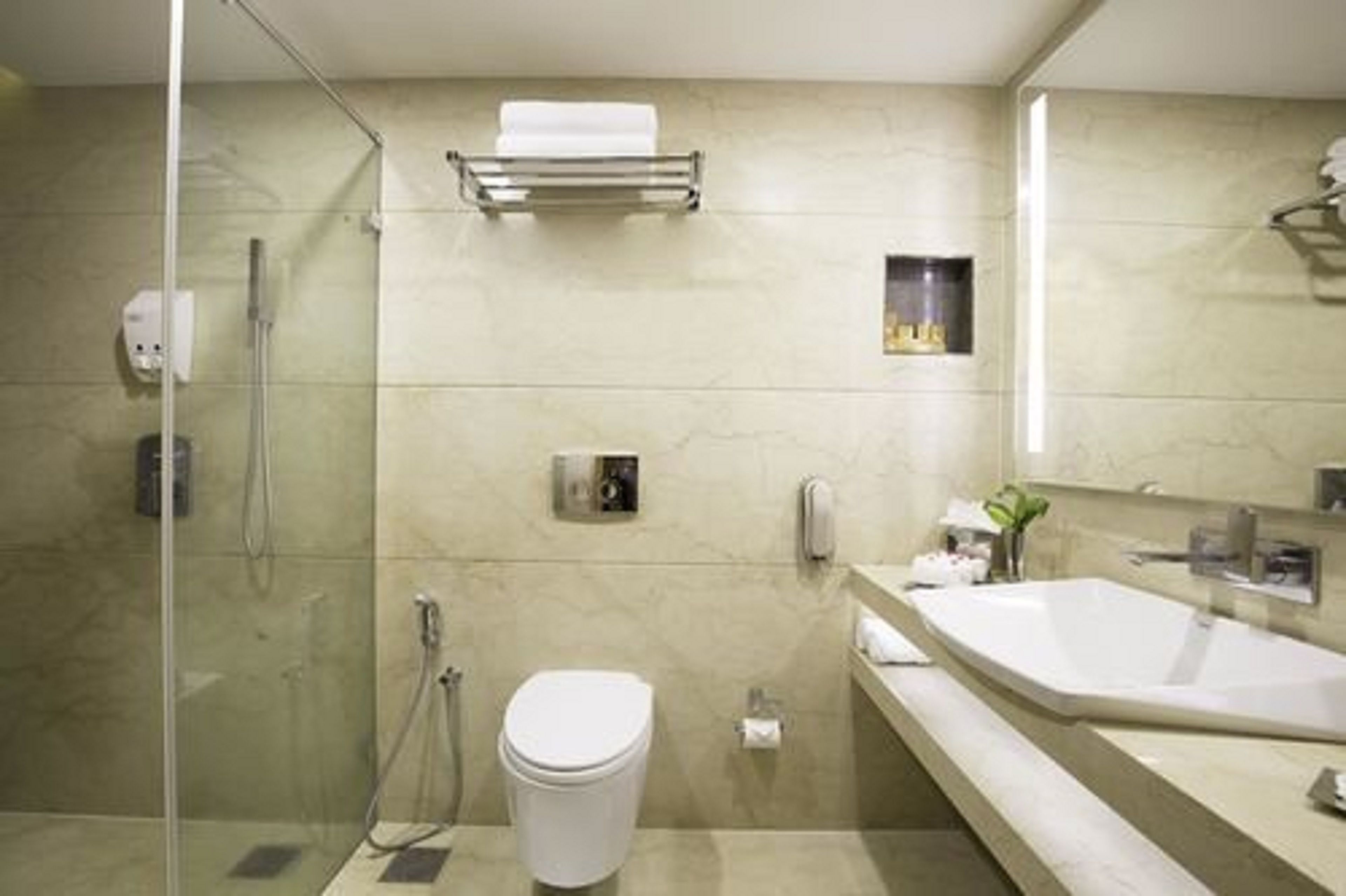 A modern bathroom with a glass-enclosed shower, a white toilet, and a large sink with a mirror.