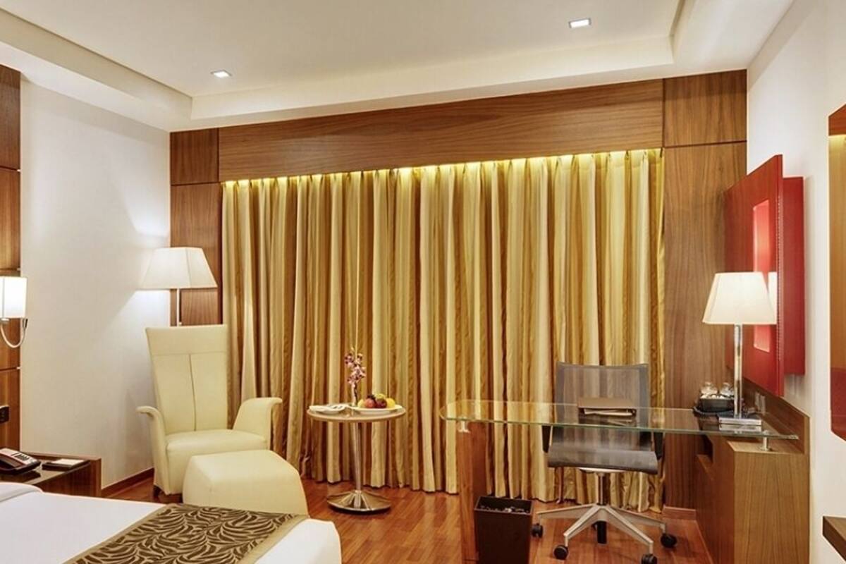 A hotel room with a large bed, a desk with a computer, a chair, and a TV.