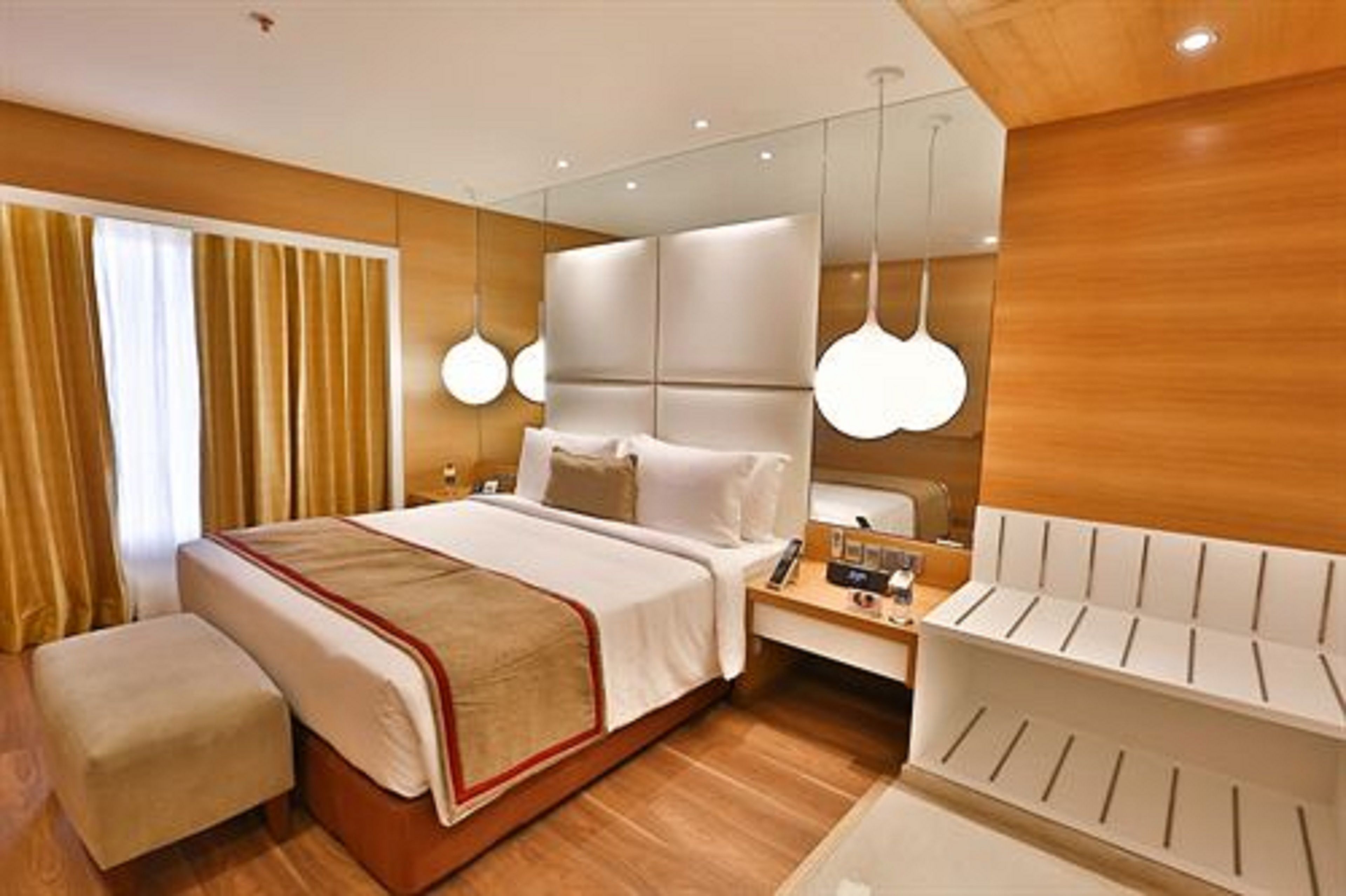 A modern hotel room with a large bed, bedside tables, and a mirror.
