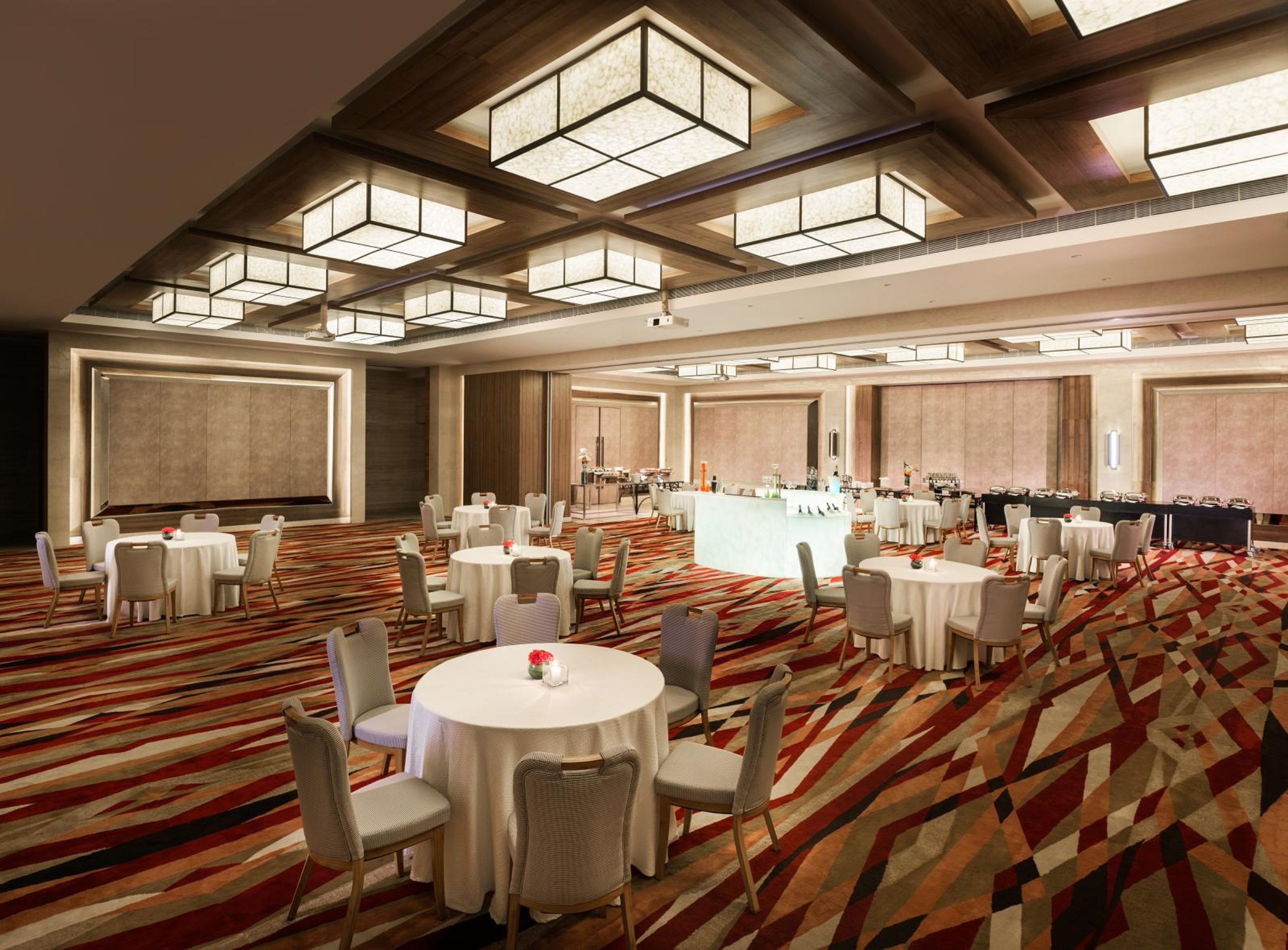 A spacious conference room with round tables, chairs, and a bar area.