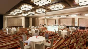 A spacious conference room with round tables, chairs, and a bar area.