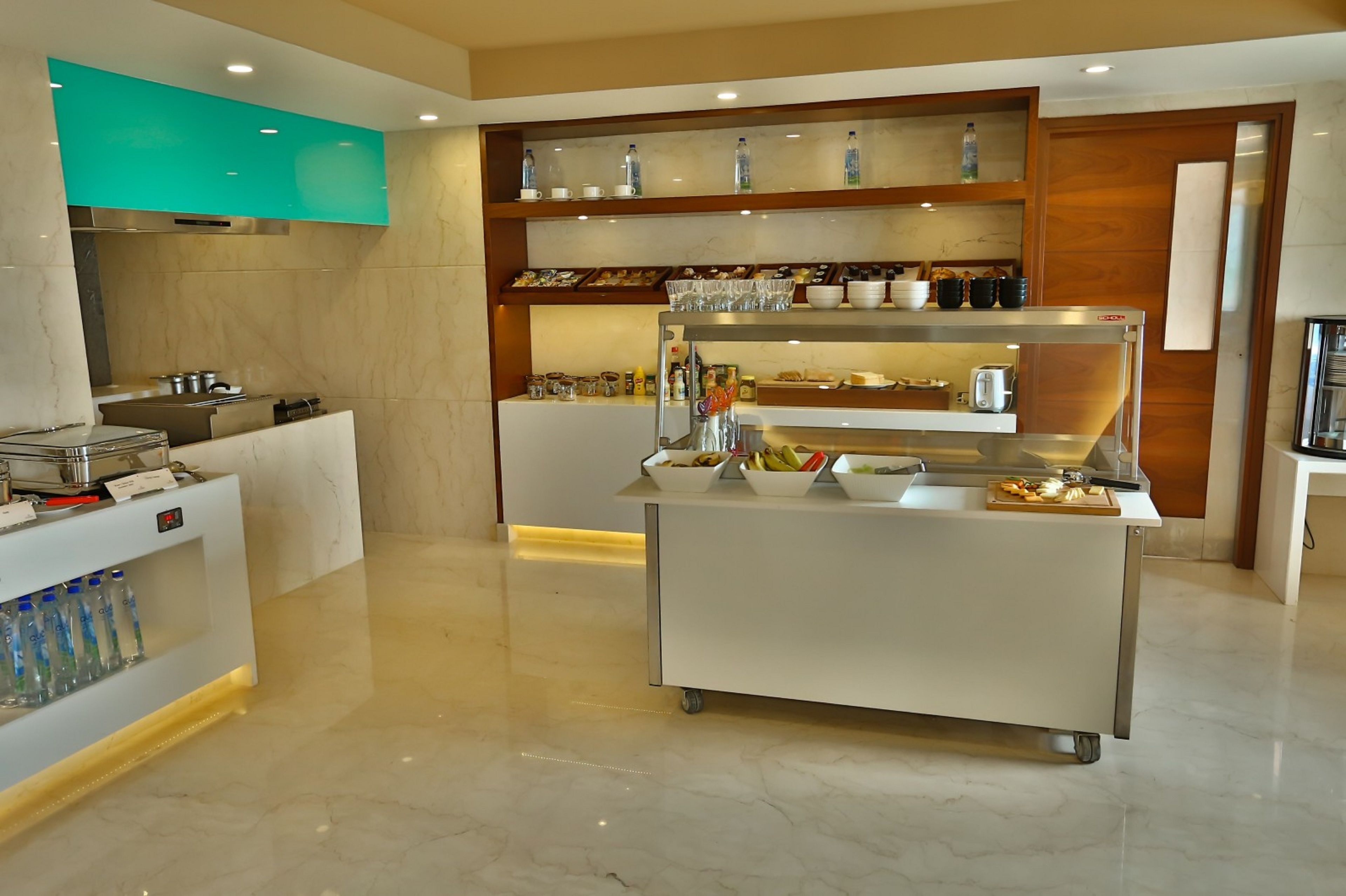 Una cocina moderna con encimera de mármol, dispensador de agua y zona de buffet con diferentes alimentos y utensilios.