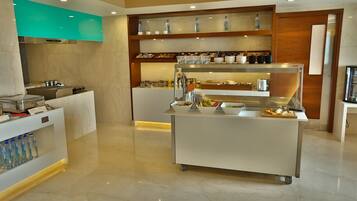 Una cocina moderna con encimera de mármol, dispensador de agua y zona de buffet con diferentes alimentos y utensilios.