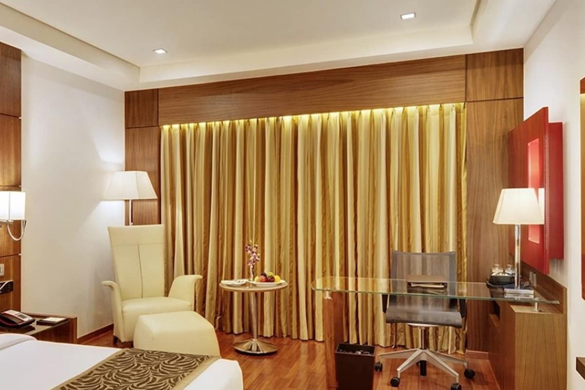 A hotel room with a large bed, a desk with a computer, a chair, and a TV.
