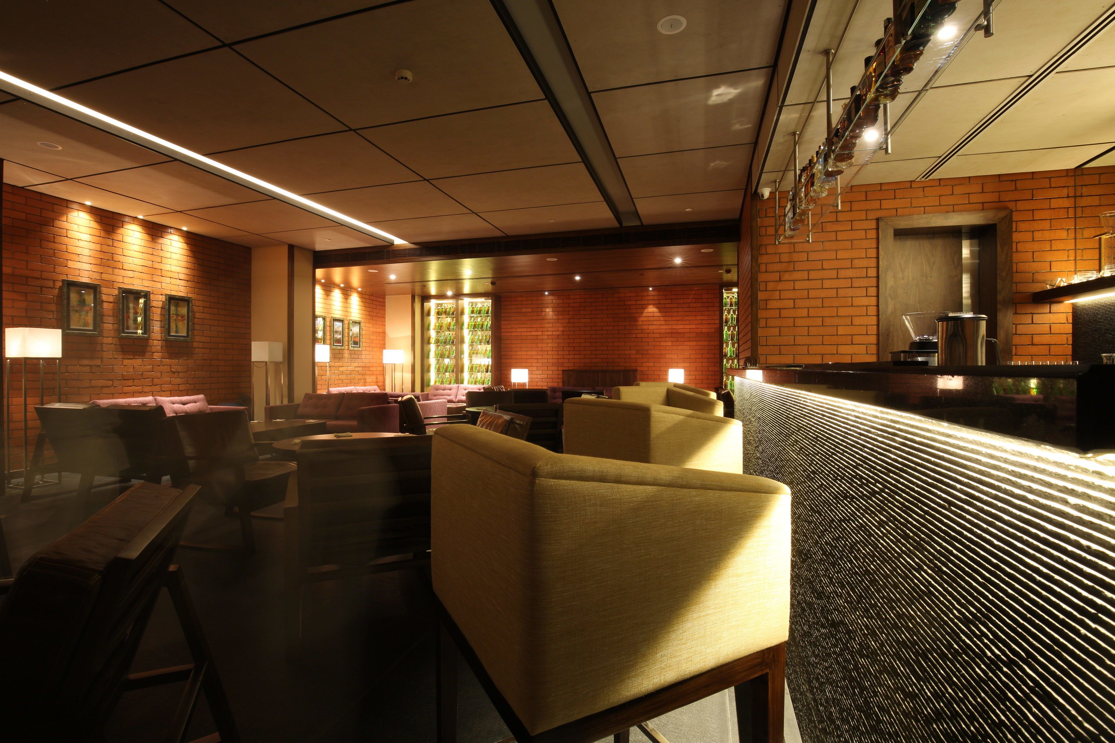 Un restaurante moderno con paredes de ladrillo, muebles de madera y una barra con dispensador de bebidas.