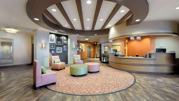 A hotel lobby with a reception desk, seating area with ottomans, and a patterned carpet. - Best Western Plus Tupelo Inn & Suites (Tupelo)