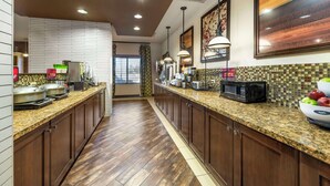 A kitchen with granite countertops, wooden cabinets, and a tiled backsplash. - Best Western Plus Tupelo Inn & Suites (Tupelo)