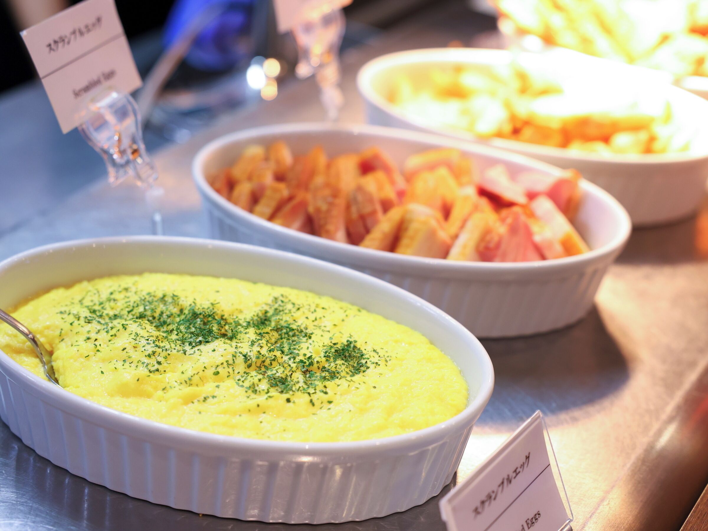 A buffet with various dishes including mashed potatoes garnished with herbs, and other food items.