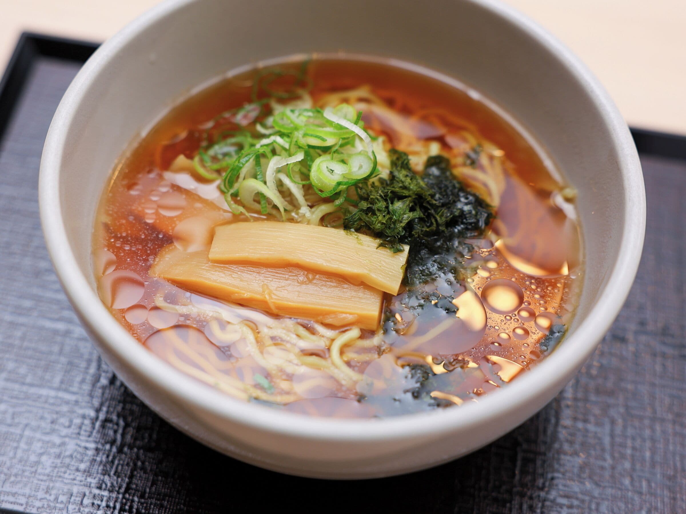 A bowl of ramen with noodles, tofu, seaweed, and green onions.