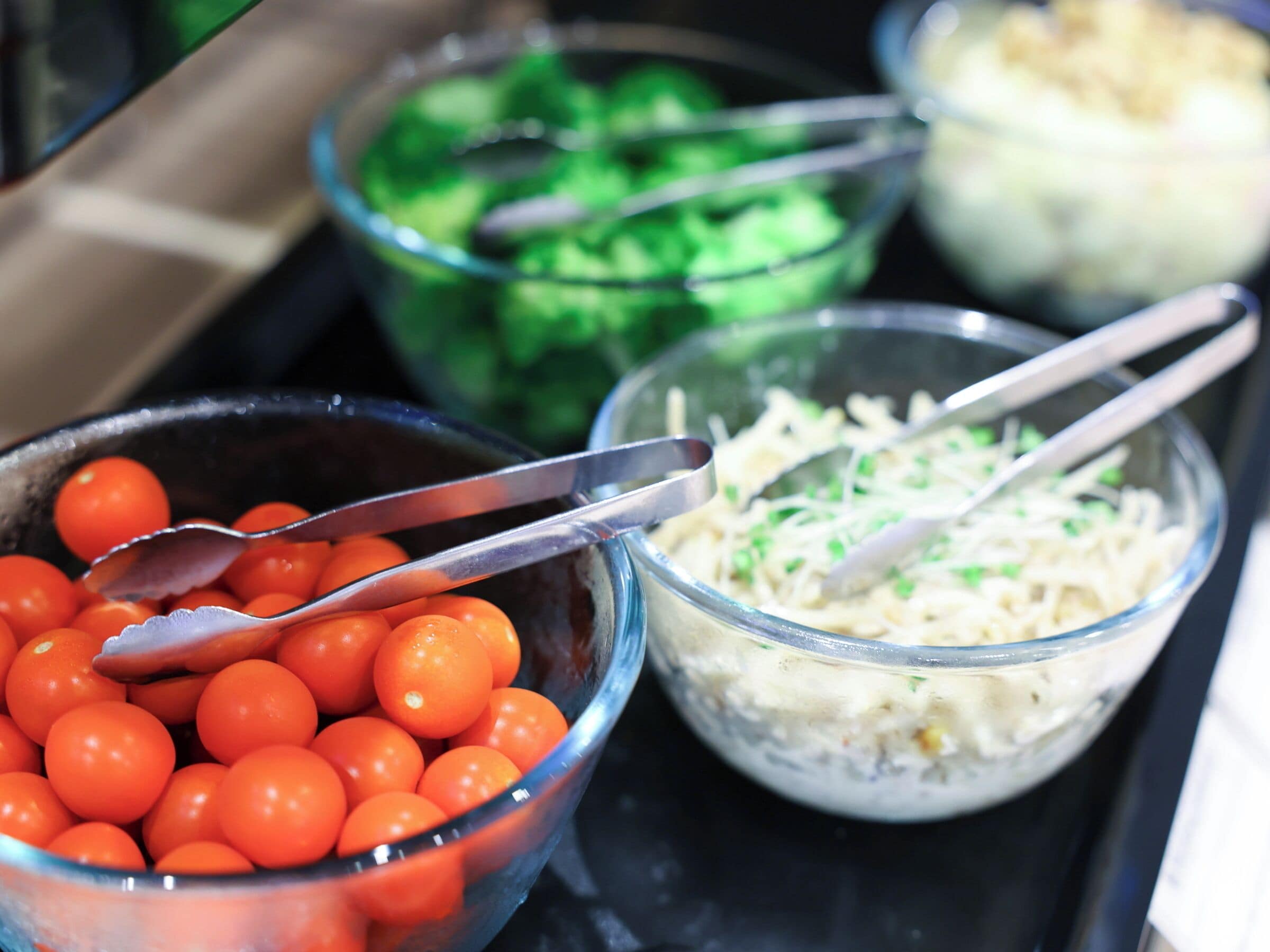 A tray with bowls containing various food items, including tomatoes, shredded cheese, and green vegetables.