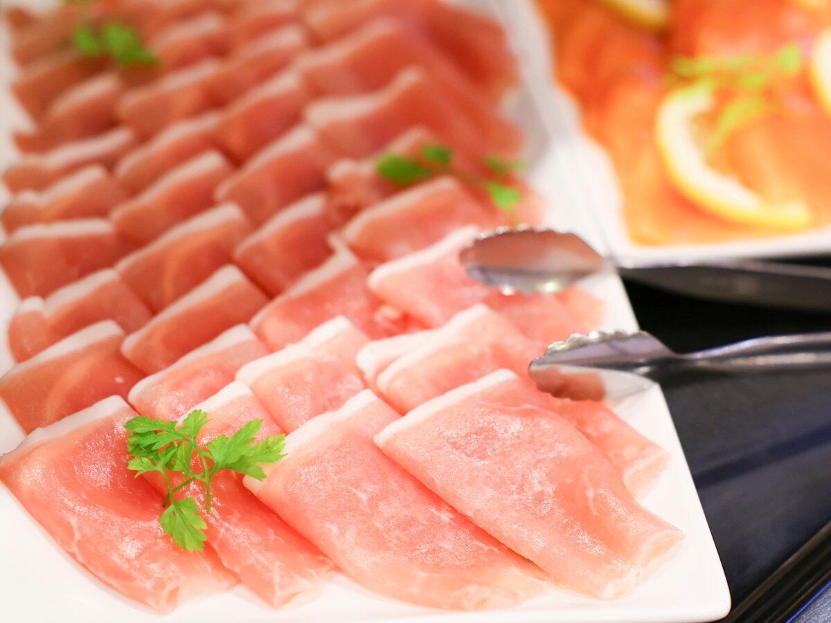A plate of thinly sliced fish arranged in rows.