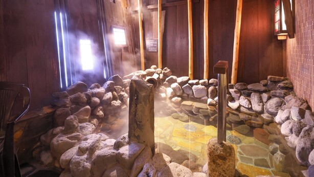 Un onsen japonés tradicional con asientos de piedra, paredes de madera y suelo de baldosas.