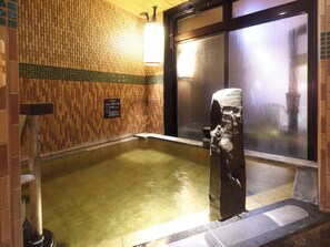 A traditional Japanese onsen with a wooden wall, a stone basin, and a glass door. - Dormy Inn Kitami Natural Hot Spring (Kitami)