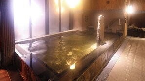 A hot spring bath with wooden walls and a tiled floor.