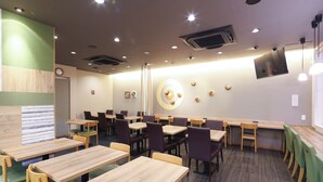 Un restaurante con mesas y sillas de madera, un reloj en la pared y un televisor montado allí.