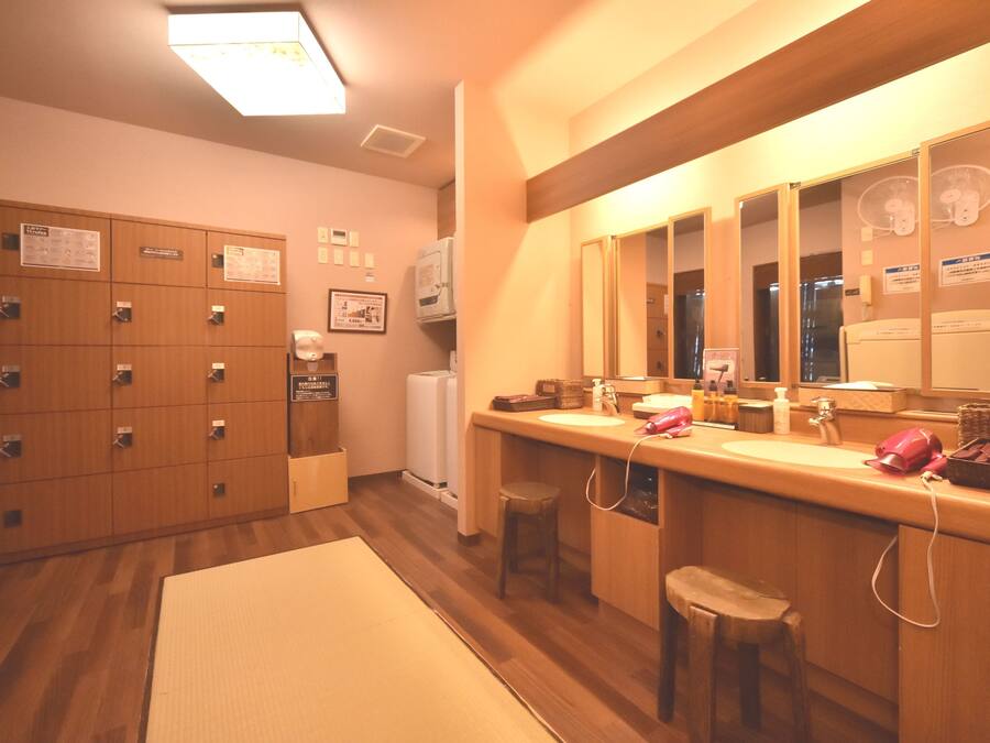 A hotel bathroom with wooden lockers, a sink, and a mirror.