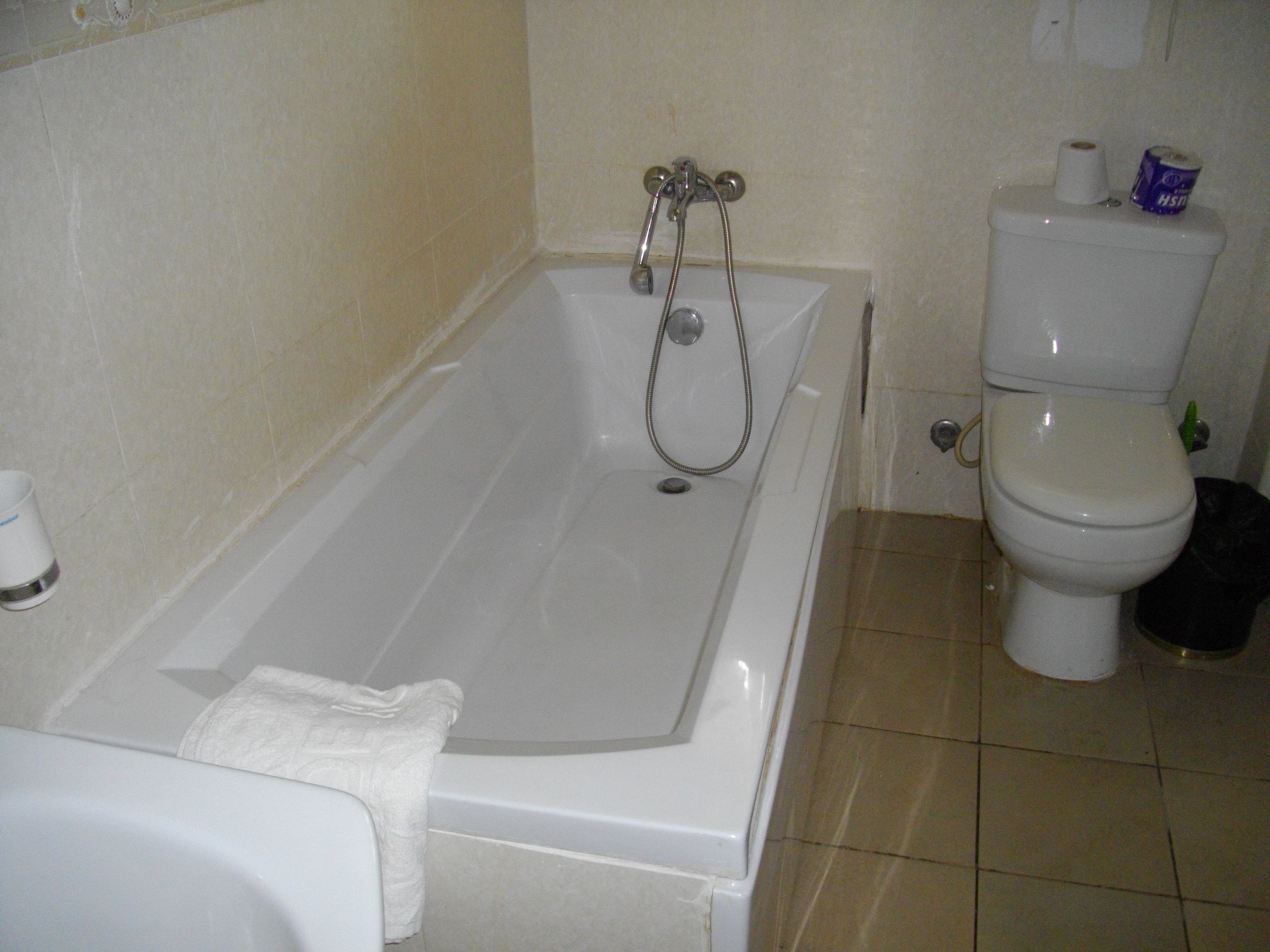 A bathroom with a bathtub, toilet, and a towel rack.