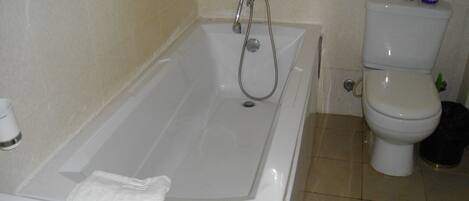 A bathroom with a bathtub, toilet, and a towel rack.