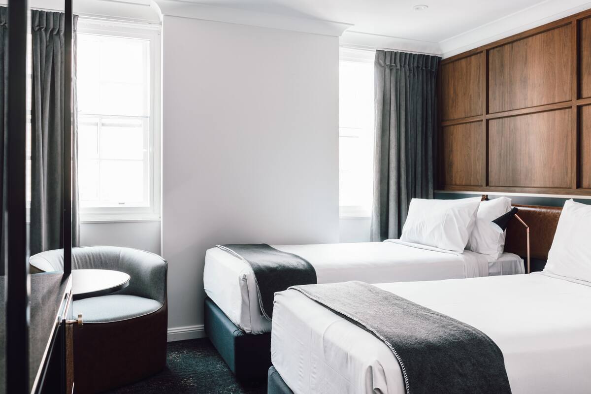 Une chambre d’hôtel avec deux lits, un coin salon et un grand mur revêtu de panneaux en bois.