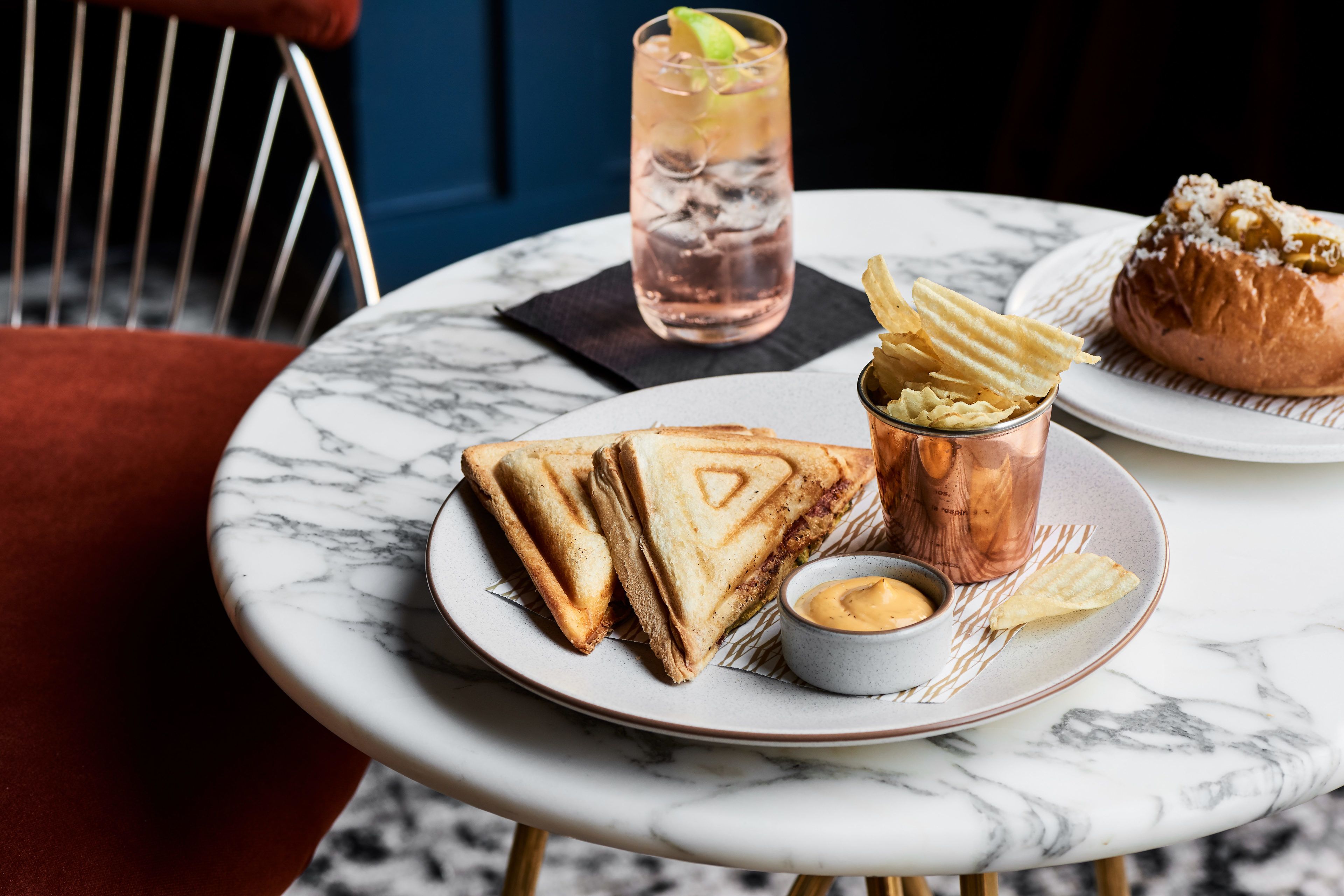 Une table avec un sandwich, des frites, une boisson et une pâtisserie.