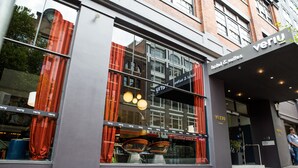 Moderni hotellin sisäänkäynti, jossa on suuret ikkunat, punaiset verhot ja kyltti, jossa lukee: ”Veriu hotel & suites”.