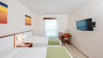 Una habitación de hotel con dos camas, un escritorio, un televisor y una ventana.
