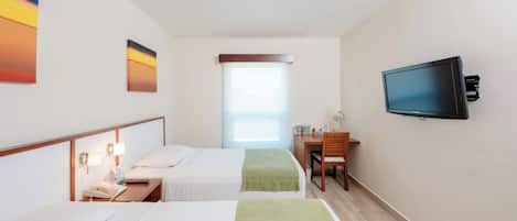 Una habitación de hotel con dos camas, un escritorio, un televisor y una ventana.