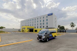Hotel CITY EXPRESS by Marriott con un estacionamiento y una camioneta estacionada frente.