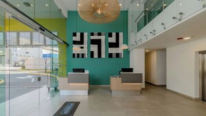 A reception area with glass walls, a green accent wall, and a modern chandelier. - City Express by Marriott Managua (Managua)