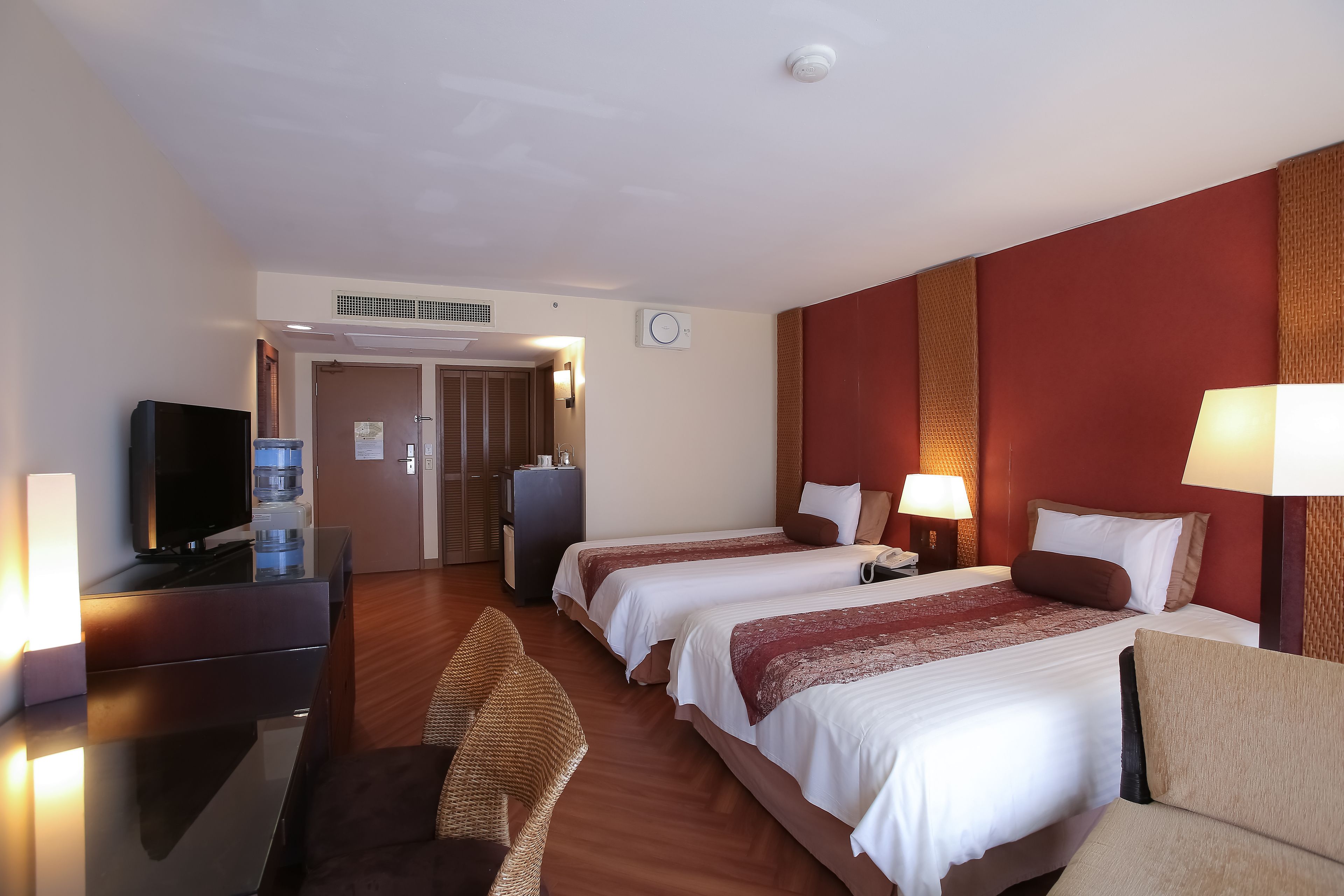 Habitación de hotel con dos camas, televisión, escritorio y una silla.