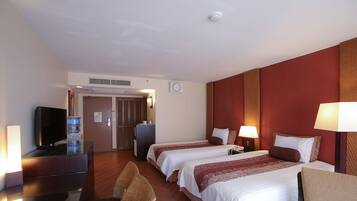 Habitación de hotel con dos camas, televisión, escritorio y una silla.
