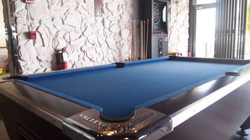 A pool table with a blue felt surface, a "Valley" logo, and a dartboard mounted above it.