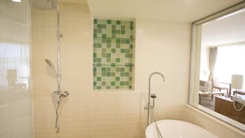 Ein Badezimmer mit einer Badewanne, einer Dusche und einer mit grünem Mosaik versehenen Fliesenwand.