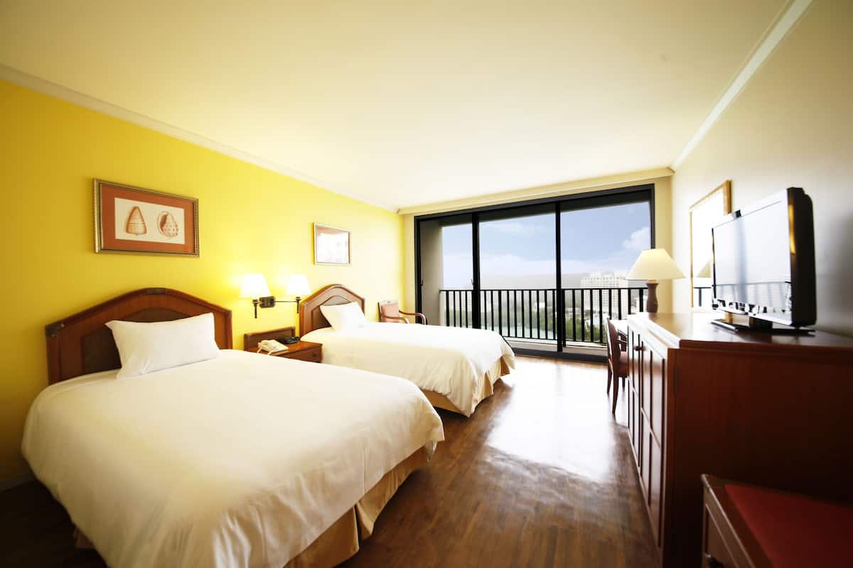 A hotel room with two beds, a balcony, and a TV.