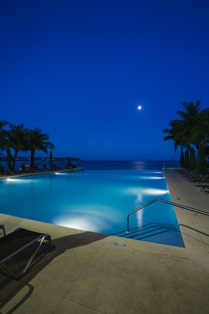 Una piscina al aire libre, sombrillas, sillones reclinables de piscina