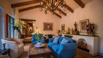 A cozy living room with a fireplace, blue sofas, a wooden coffee table, and a chandelier.