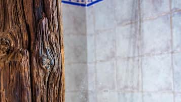 A wooden door frame and a tiled shower area with a showerhead and a small shelf.