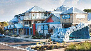 A modern hotel with a blue and white color scheme, featuring a large ice sculpture in front, a parking lot, and a sign indicating the hotel name and location. - The Island Accommodation (Newhaven)