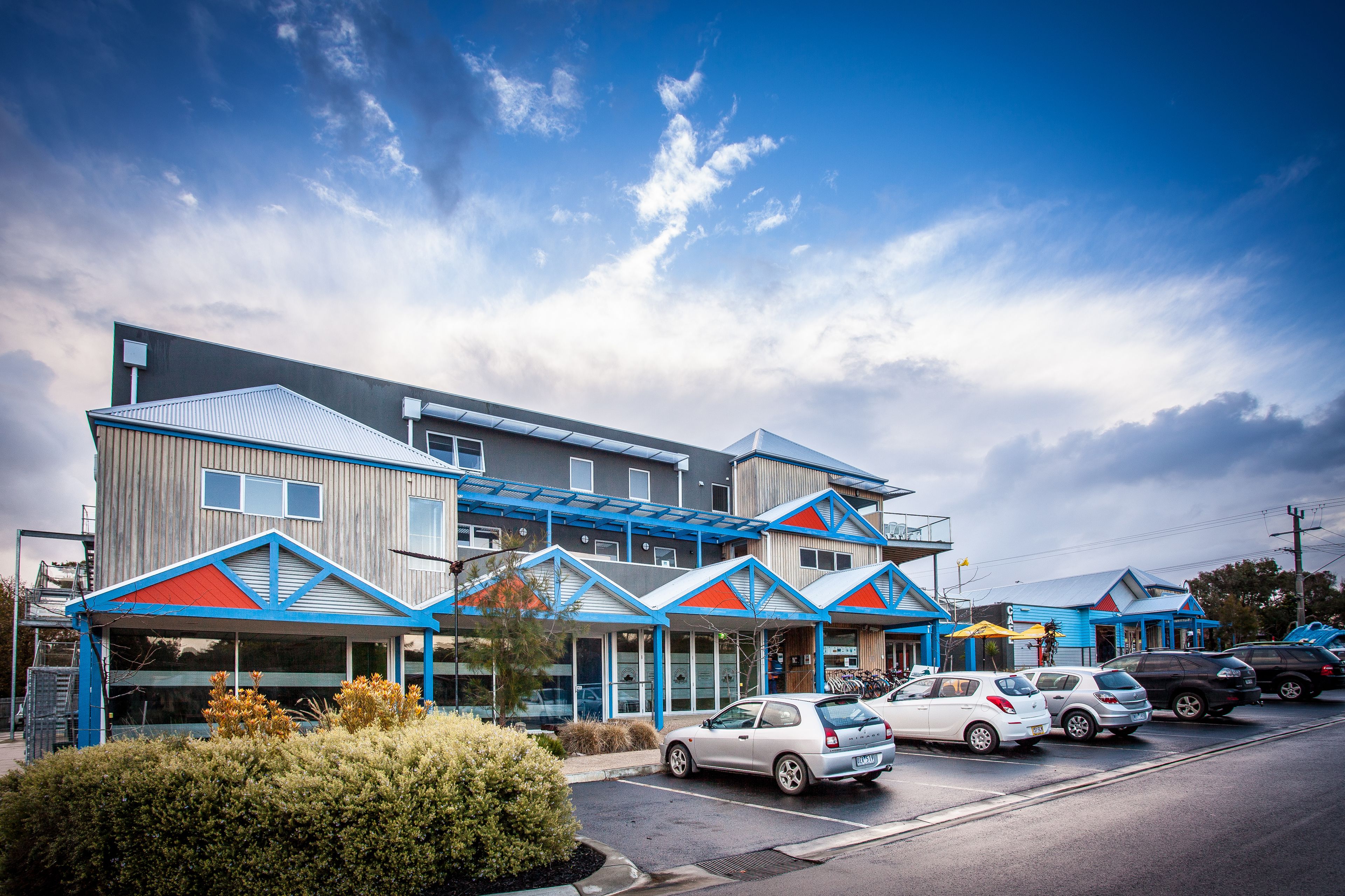 A modern hotel with multiple levels, large windows, and a covered parking area.